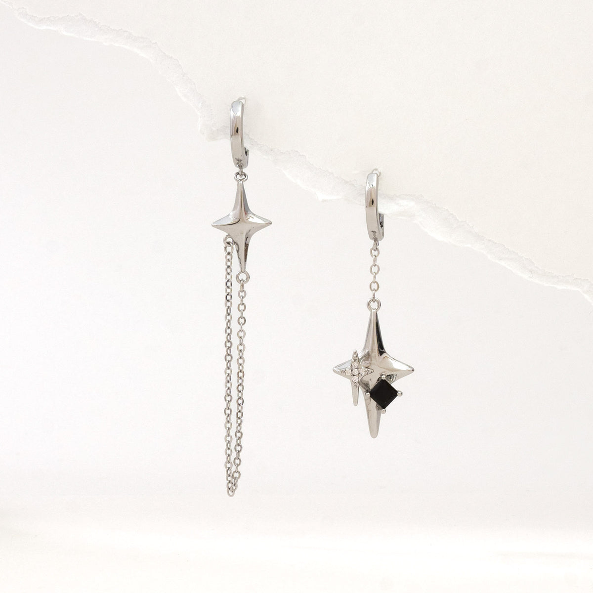 Silver asymmetric 4-point star earrings – on white background
