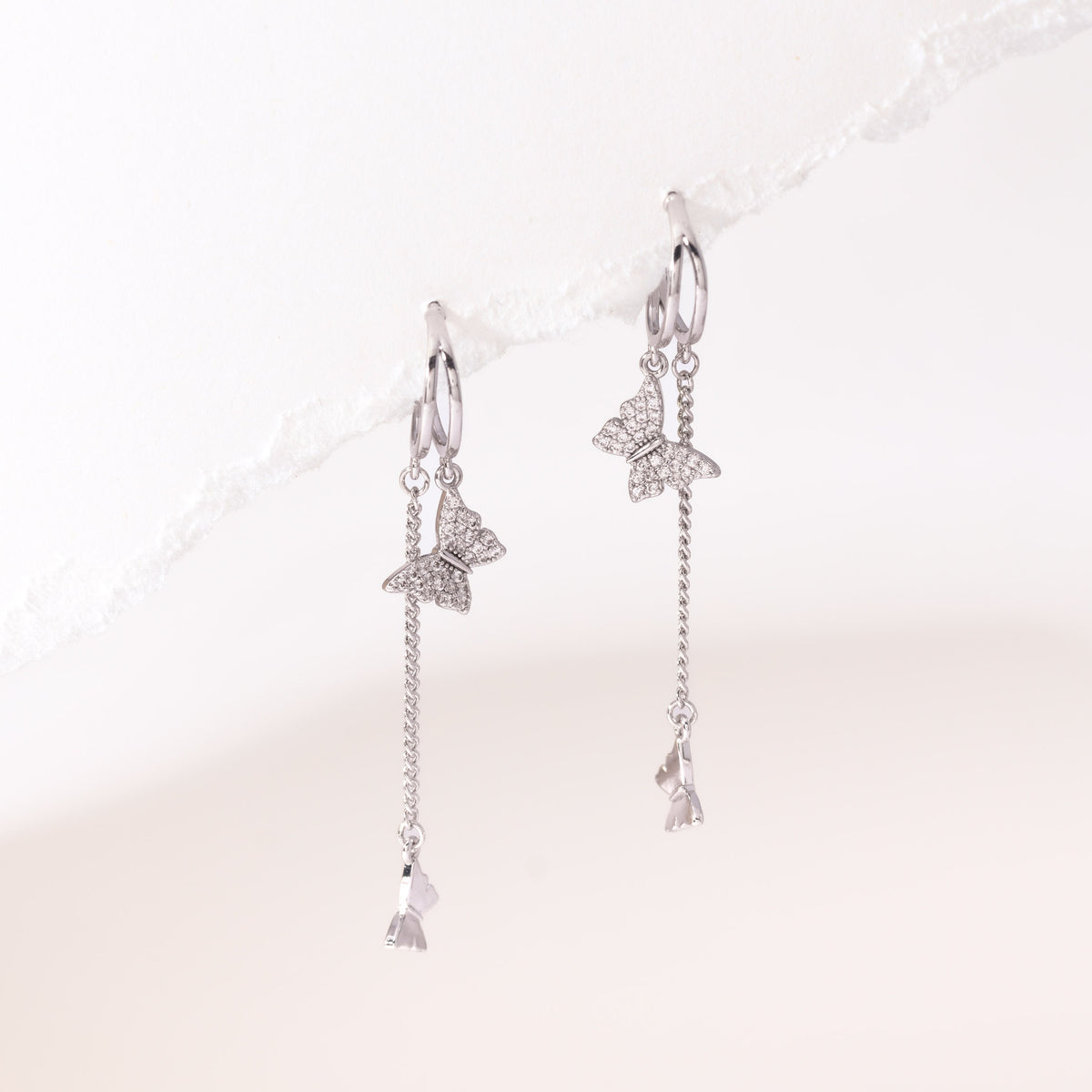 Silver dangling butterfly earrings – on white background